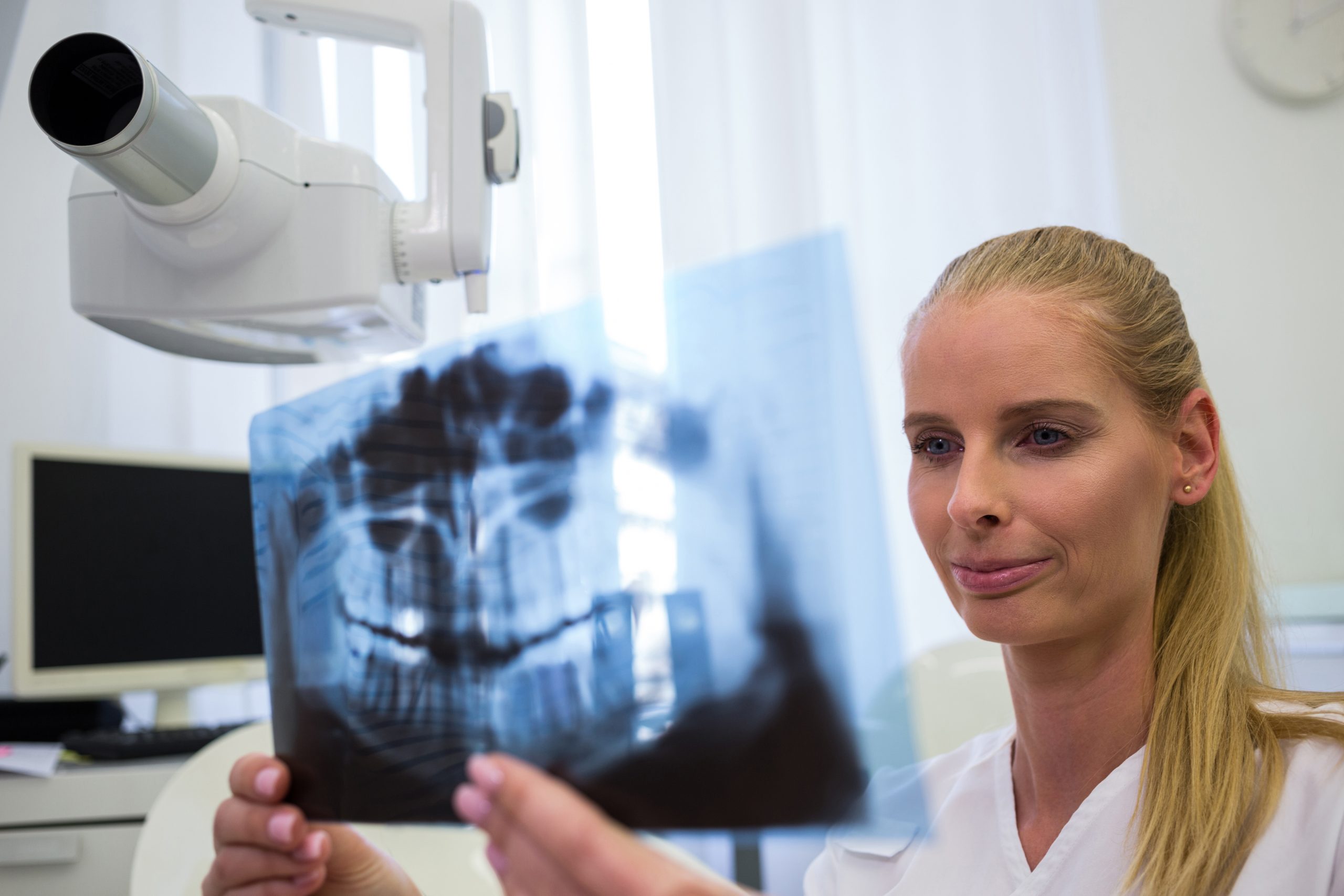 Dentist looking at dental x-ray plate in clinic