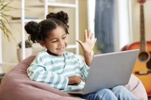 Proteção digital: 34 anos do Estatuto da Criança, com seus desafios e avanços. 1 menina negra acenando para a camera do laptop e sorrindo 236854 47342